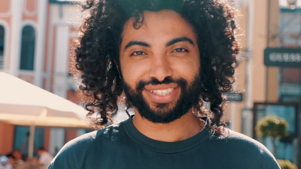 hombre sonriente con el cabello rizado al aire libre