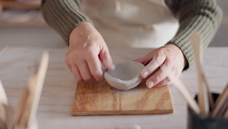 Clay-bowl,-woman-hands-and-sculpture-in-artist