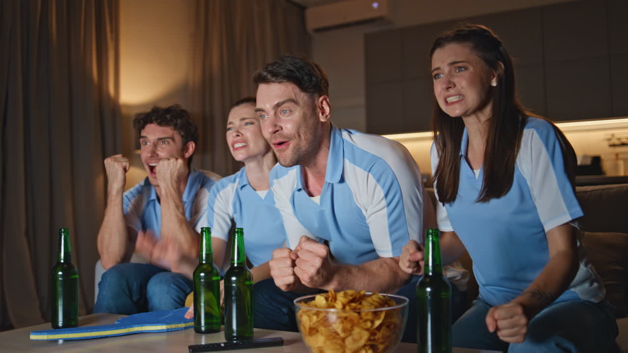 Emotional mates cheering football match at night home close up. Fans watching tv