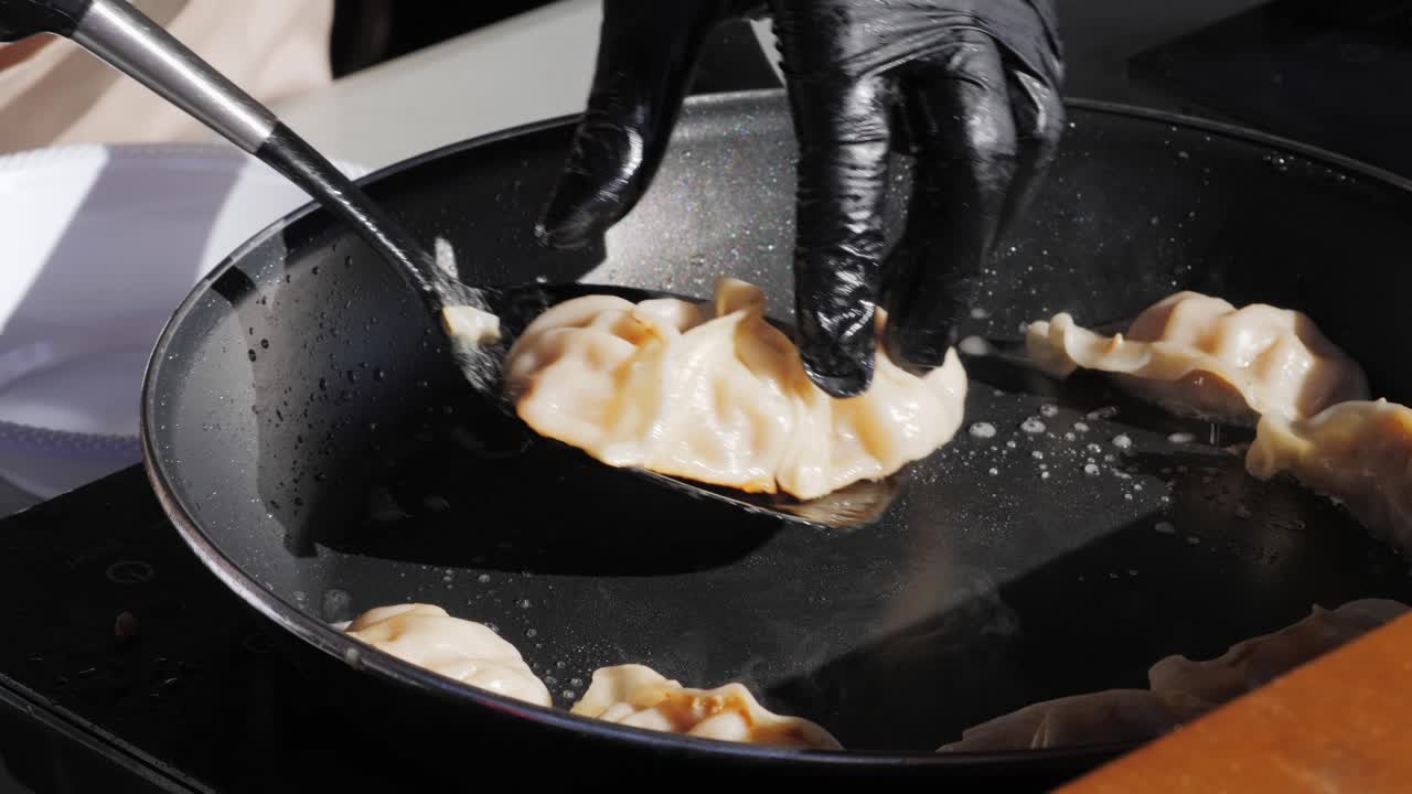 Cooking Chinese and Japanese gyoza in boiling oil close-up. Dumplings with meat pouring red sweet chilli sauce. Cooking at cafe, restaurant. Asian street food market outdoors.High quality 4k footage