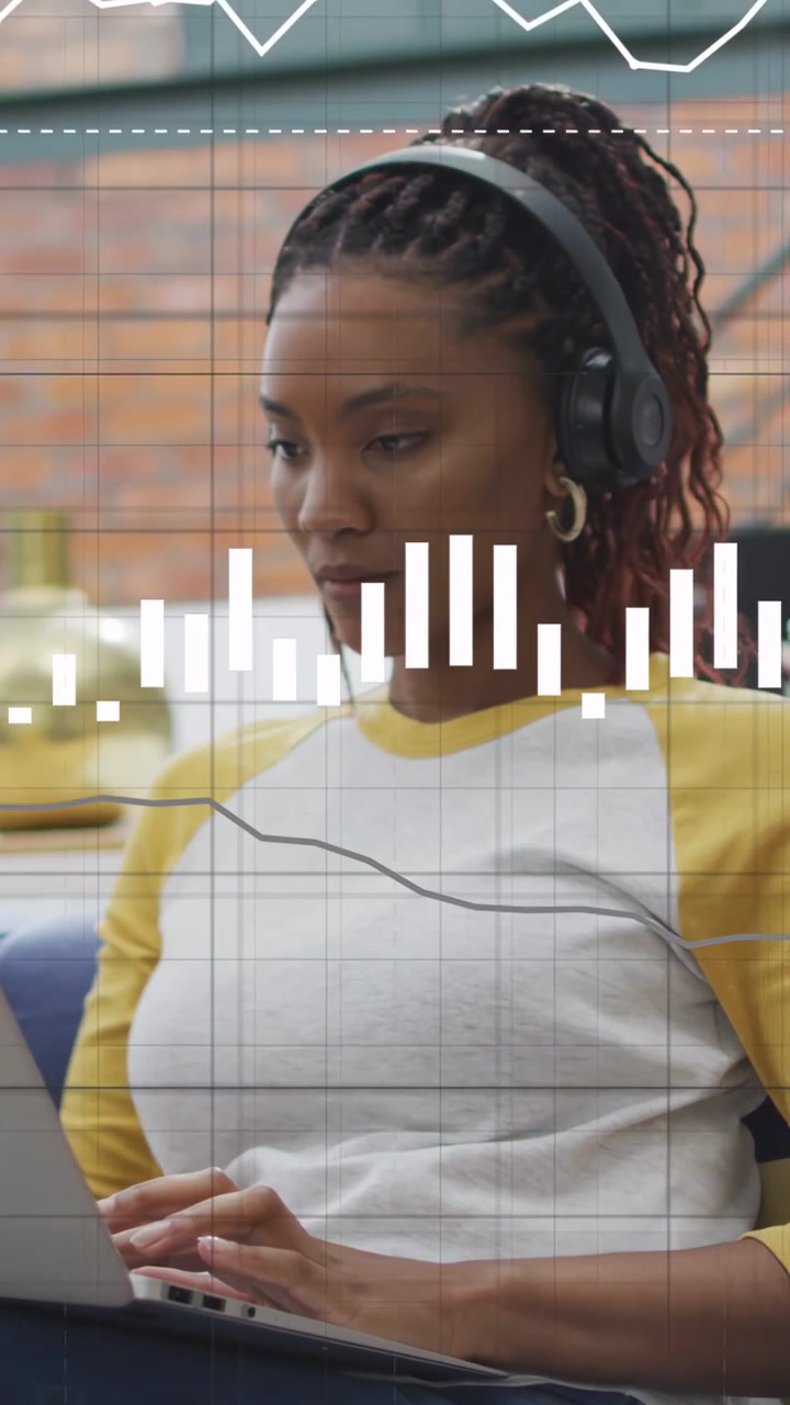 Vertical video: Woman typing on laptop causing animated bars expanding into finance charts overhead