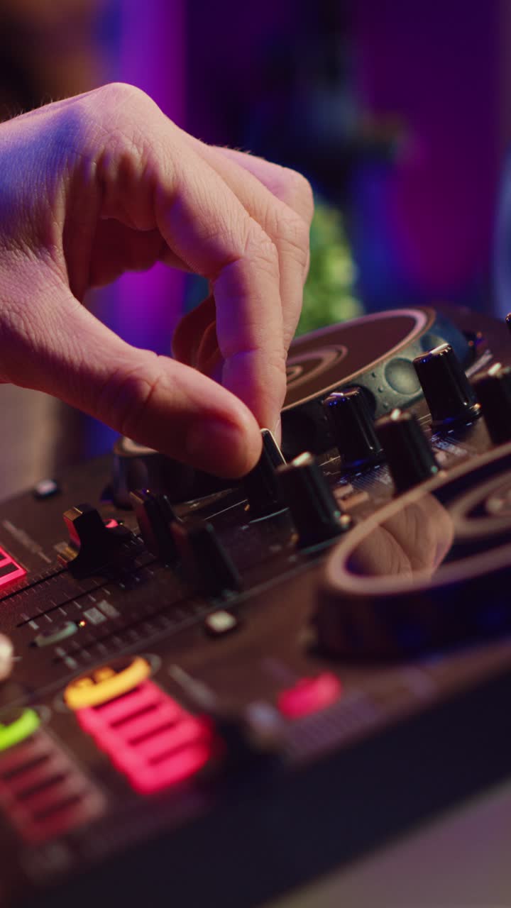 Primo piano delle mani di un DJ che mixa musica su una console con luci al neon