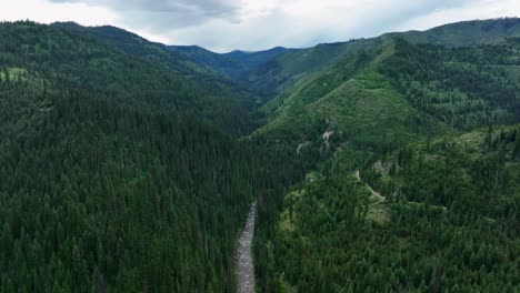 Vista-Aérea-Del-Río-De-Montaña,-Montañas-Cubiertas-De-árboles-Coníferos---Disparo-De-Drones