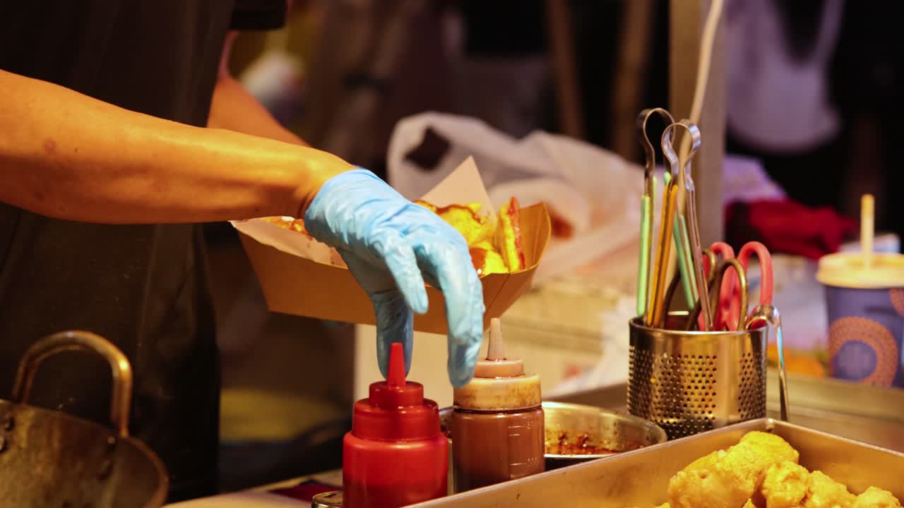 vendedor preparando comida con salsas y ingredientes