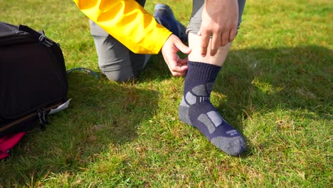 detail shot of a guy peeling off a hiking sock on the grass