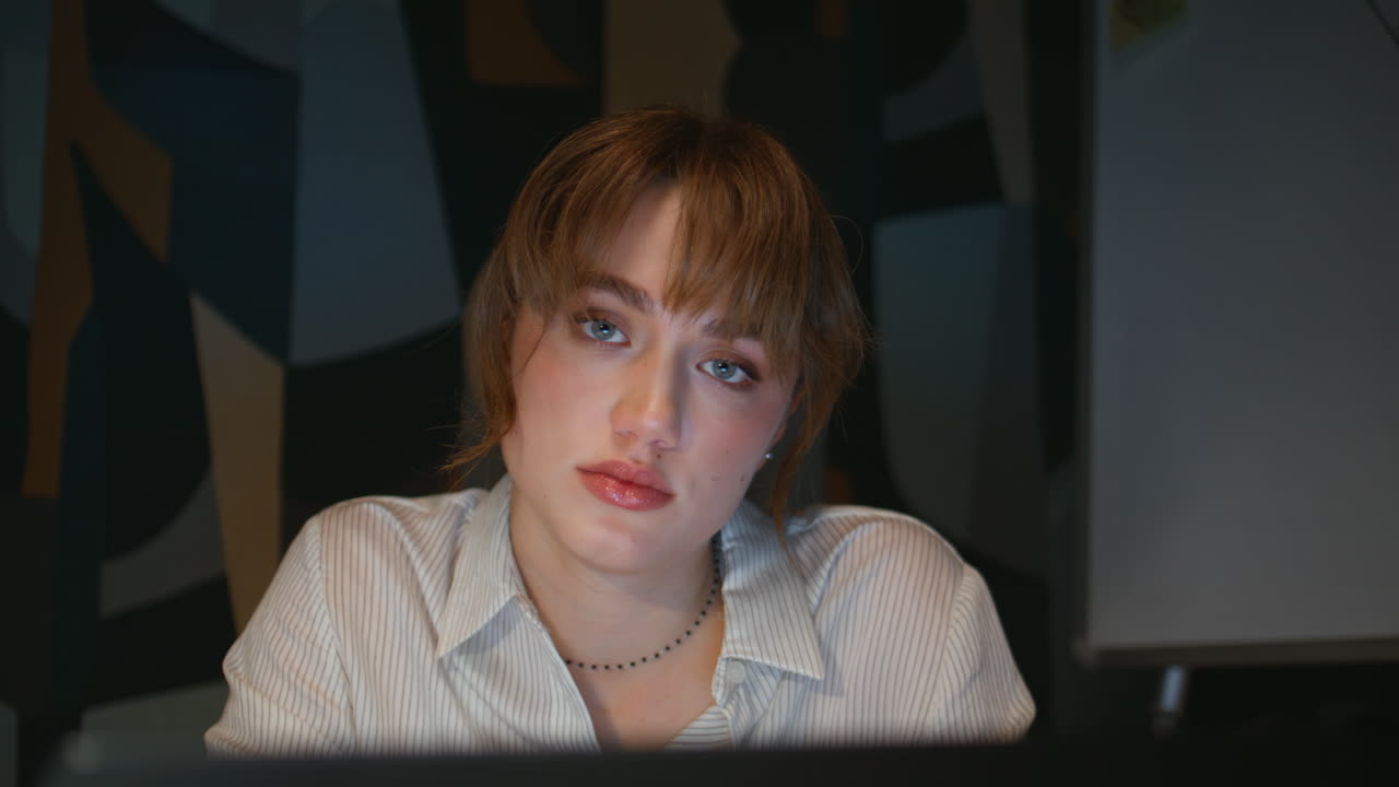 Unmotivated manager staring laptop feeling sleepy at evening workplace closeup