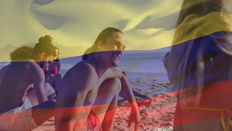 animation of flag of colombia waving over diverse friends sitting and enjoying at beach