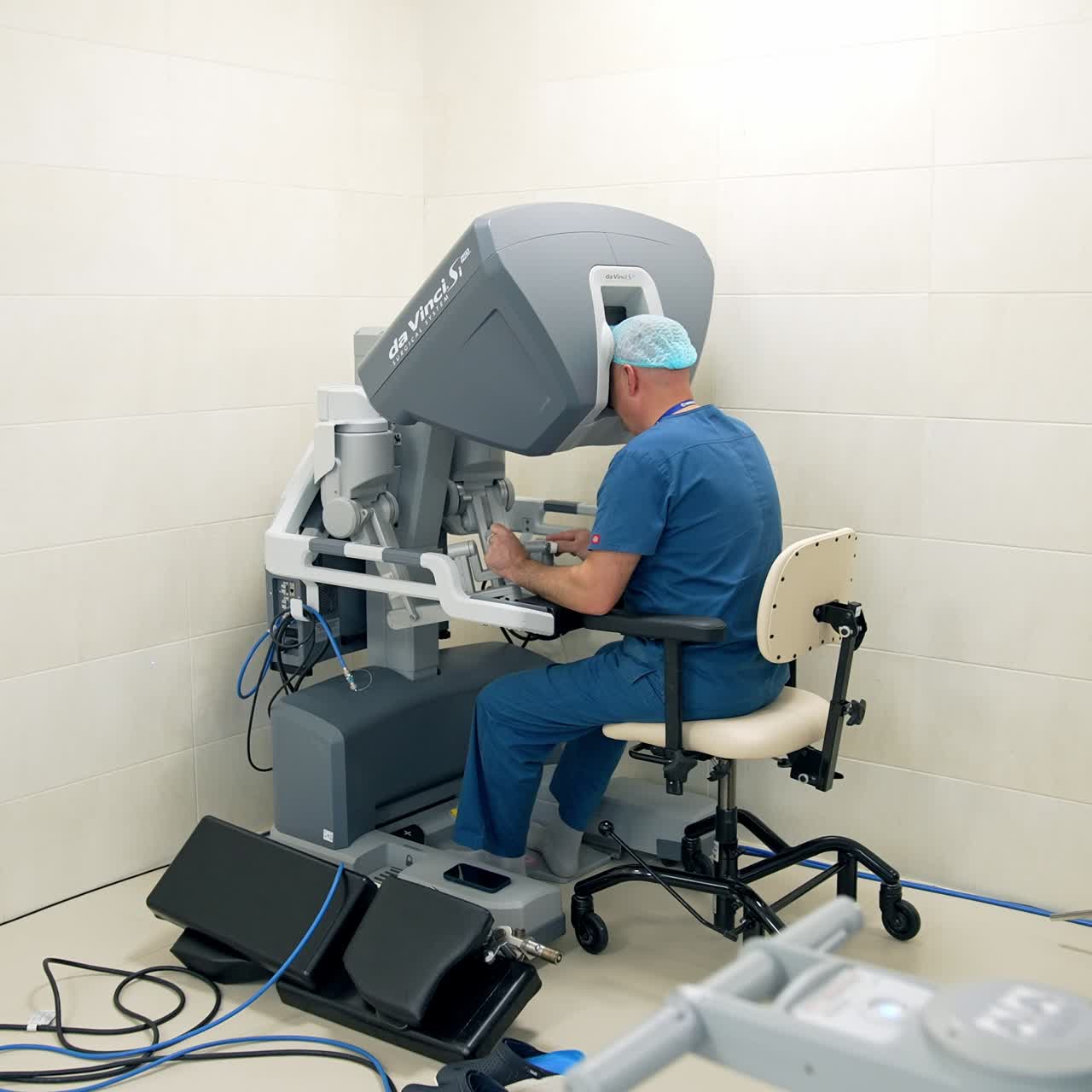 Medical specialist wearing blue uniform sitting at futuristic robotic apparatus. Doctor is managing high technology machine. Gradual distancing footage