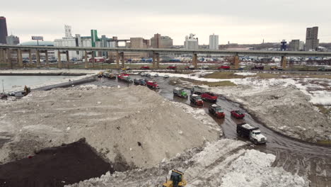 29 december 2022 - aerial flying over snow storage site with queues of trucks lining up beside buffalo highway in new york