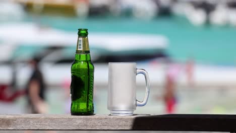 botella de cerveza y taza a la orilla del mar