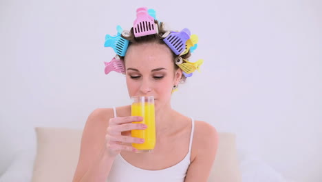 young model in hair rollers drinking glass of orange juice