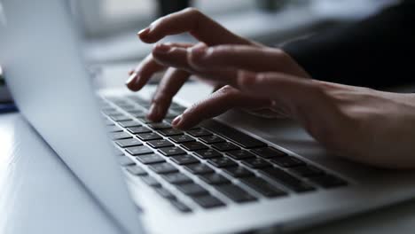 unrecognizable female hands typing something on laptop keyboard.