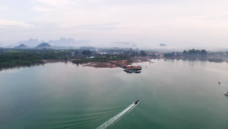 barco de cola larga navegando hacia el muelle en la nebulosa costa del océano de tailandia