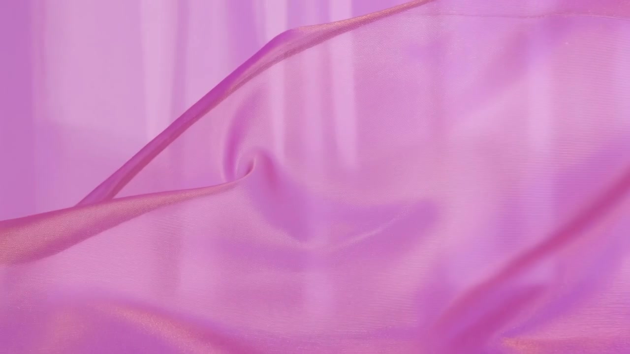 Una superficie setosa trasparente simile a un nastro si muove delicatamente attraverso l'inquadratura con pieghe mutevoli e contorni fluidi, mostrando toni rosa e viola, illuminazione soffusa e movimento astratto.