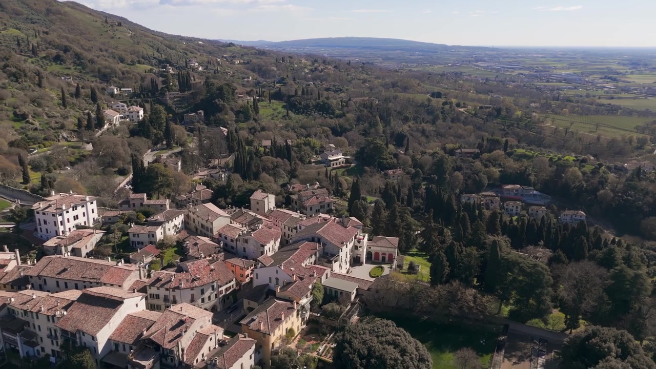 Veduta aerea con drone sui tetti di villaggi storici e colline lussureggianti nel Veneto rurale, Italia.