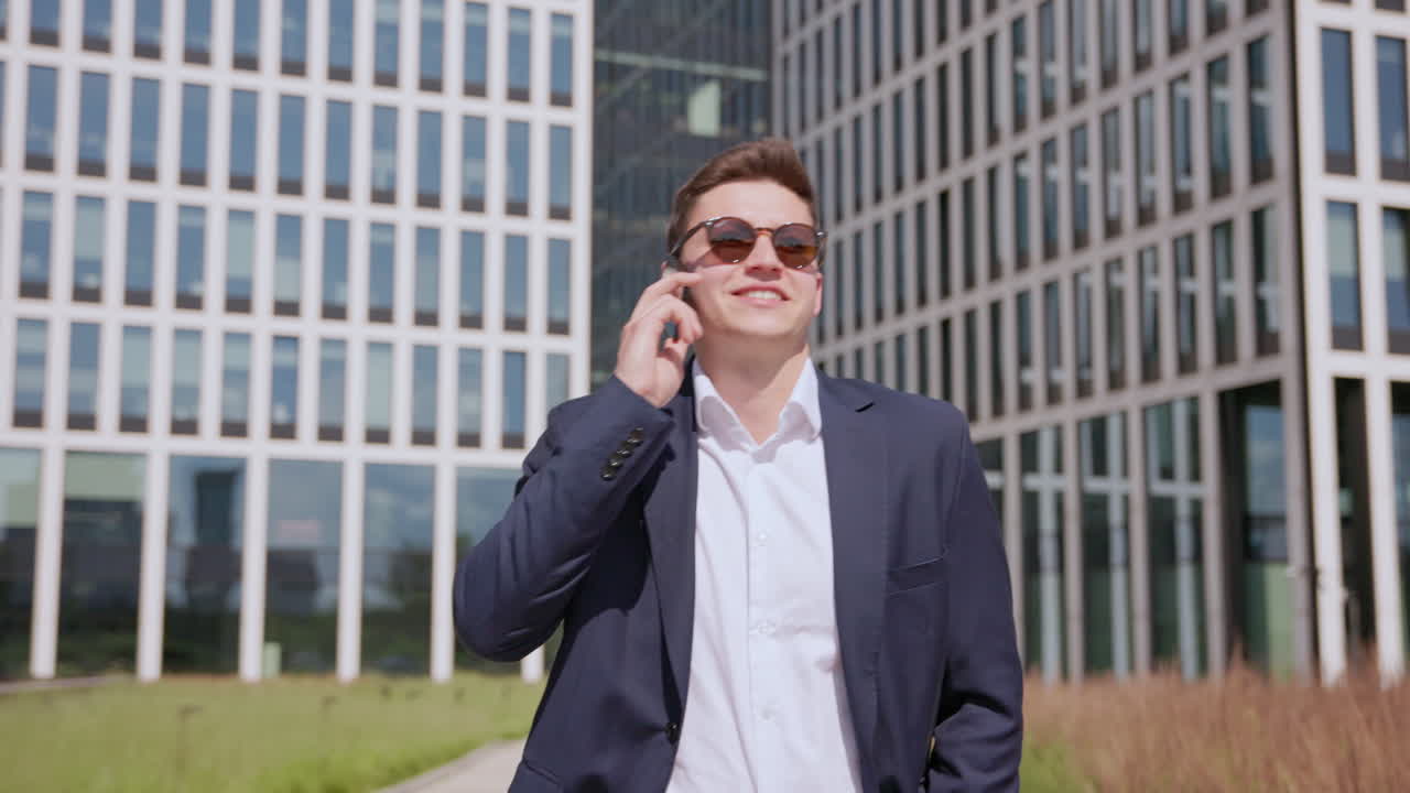젊은 행복 한 기업가 가 현대적 인 사무실 건물 앞 에서 전화 로  ⁇ 고 이야기 하고 있다