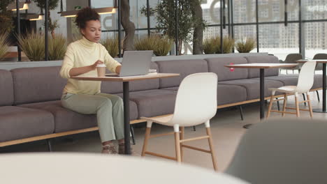 biracial woman drinking coffee in coworking