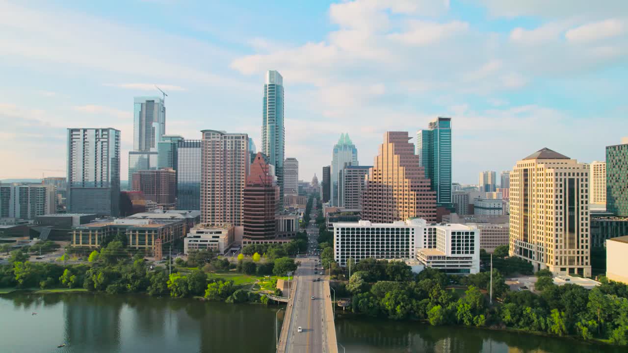 fotografia aérea de um drone da ponte da avenida do congresso de austin, texas, com vista para o capitólio do estado do texas e o horizonte do centro da cidade de austin no rio colorado ao pôr do sol, com carros, motociclistas e pedestres