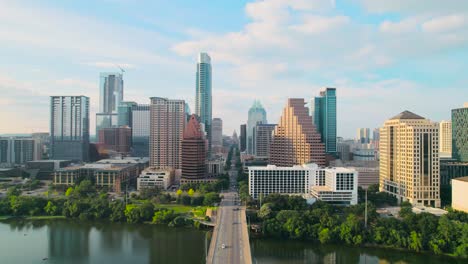 aerial drone shot of austin texas' congress avenue bridge overlooking the texas state capitol and downtown austin city skyline on the colorado river at sunset, with cars, bikers, and pedestrians