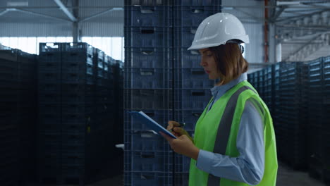 Female-warehouse-worker-checking-shipment-boxes-inspecting-delivery-package
