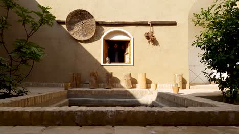 a girl opens the wooden window and smile in an old house built with mud in a historical village in desert in iran