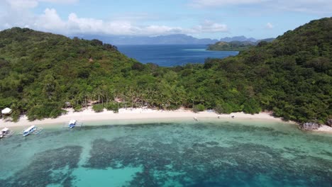 coco beach of bulalacao island in coron, philippines with escapade tour boats and people by resort huts