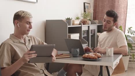 gay couple using gadgets and having talk at home