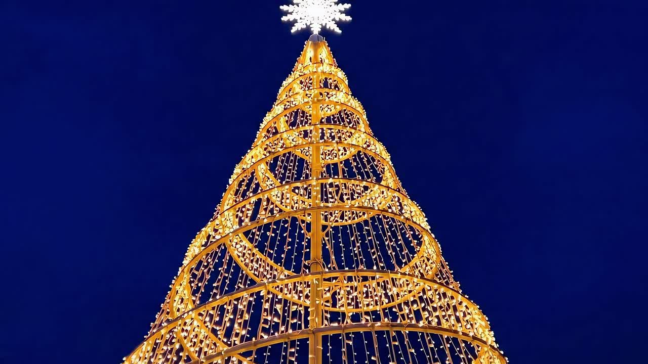 Low-angle video of a towering spiral light display against a deep blue evening sky