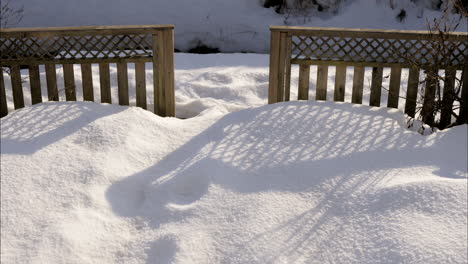 Statischer-Zeitraffer-Des-Schattens-Des-Holzzauns,-Der-Sich-Auf-Schnee-Im-Hinterhof-Bewegt