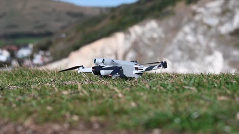 un dron gris está sobre la hierba, listo para despegar, equipo de filmación, tecnología