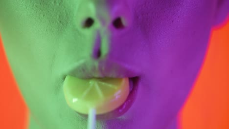 close up shot of beautiful full sexy lips of a young woman licking a lick sweet lollipop with the shape of a lemon and letting her tongue roam over the lips in slow motion