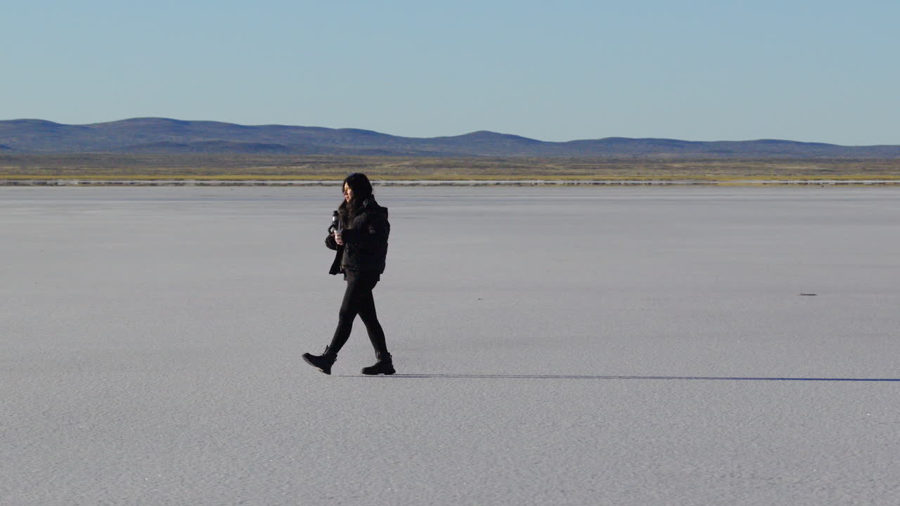 Female traveler enjoys yerba mate while exploring remote salt desert in Argentina, cultural and nature retreat