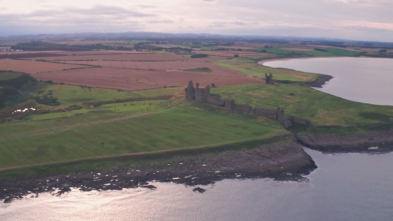Ruins of Dunstanburgh Castle at sunset, Northumberland, England, UK. Aerial drone view