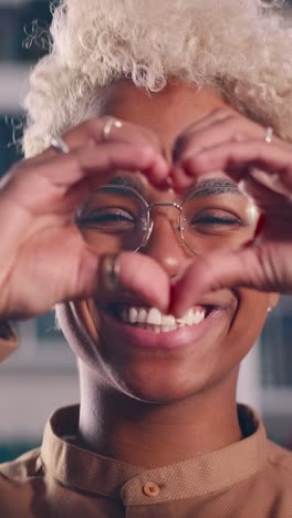 young laughing romantic african american woman making heart shape from fingers