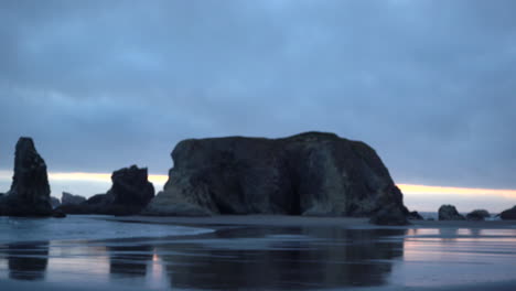 Stimmungsvolle-Küstenlandschaft-Mit-Felsnadeln-In-Bandon,-Oregon,-Pazifischer-Nordwesten,-Schöne-Spiegelungen-Im-Sand,-Heranzoomen