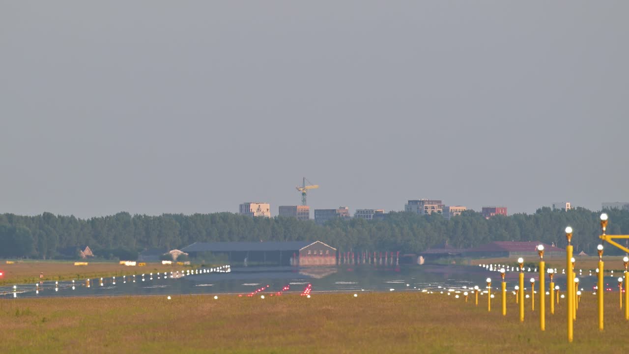 Video of an airplane landing on the runway from the edge of it.