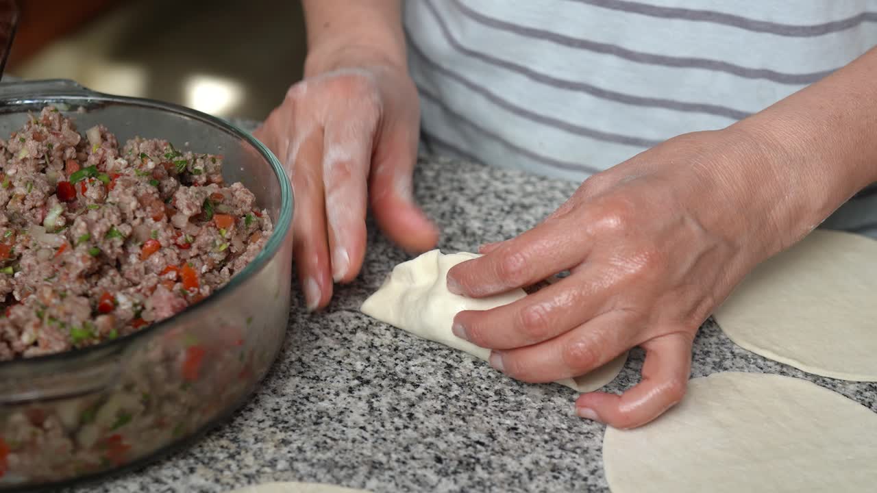 Close-up of woman's hands making meat fatayers also known as Middle Eastern savory hand pies