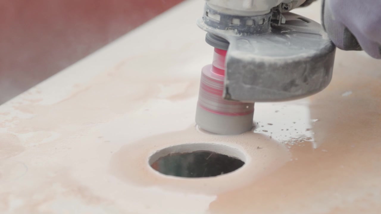 Cutting a hole with a circular power tool in a ceramic tile. Contractor working.