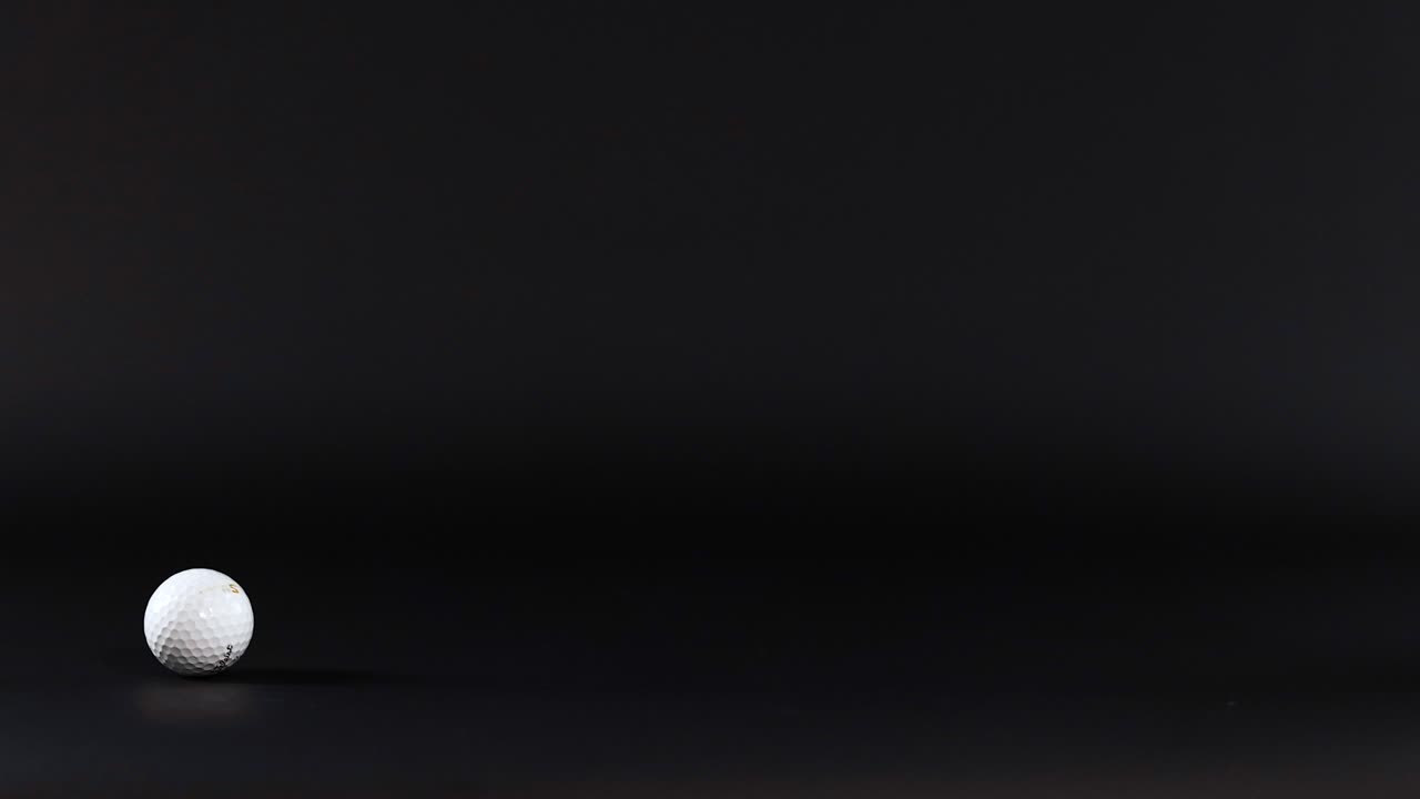 A golf ball rolls across a dark surface