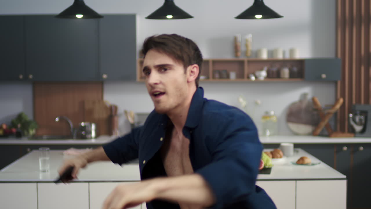 현대적인 부 ⁇ 에서 춤추는 활기찬 남자. 웃는 남자 집에서 손가락을  ⁇ 러