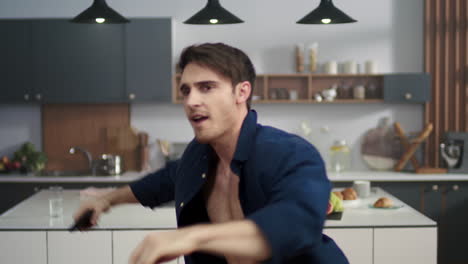 hombre enérgico bailando en la cocina moderna. tipo sonriente chasqueando los dedos en casa