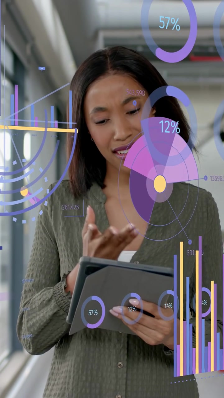 Vertical video: Female analyst tapping tablet and swiping charts in office corridor, updating KPIs