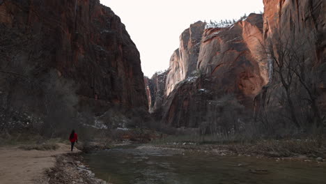 woman walking next to a flowing river in the zion national park