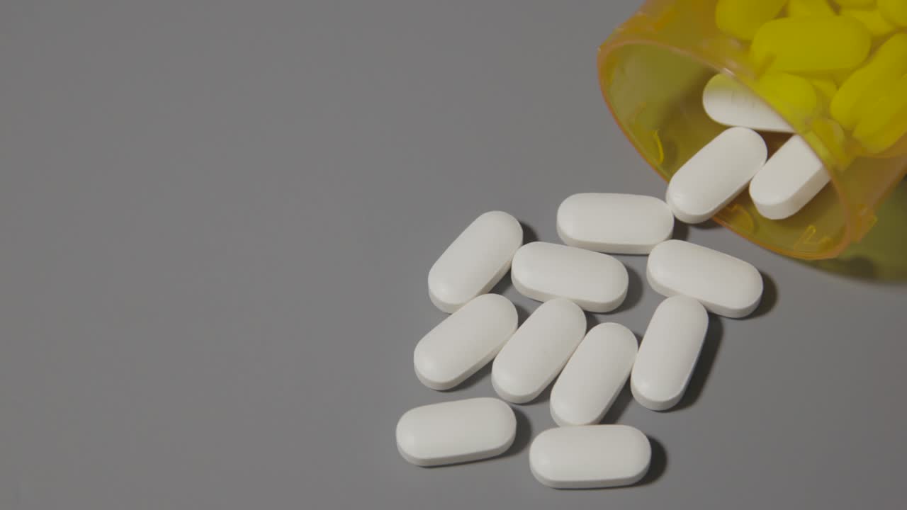 opioid pills spilled out on table for health addiction pain medicine neutral gray table