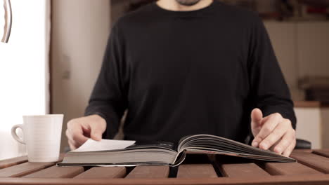 time lapse: attractive caucasian man is studying for university while drinks a cup of tea or coffee on a wooden table