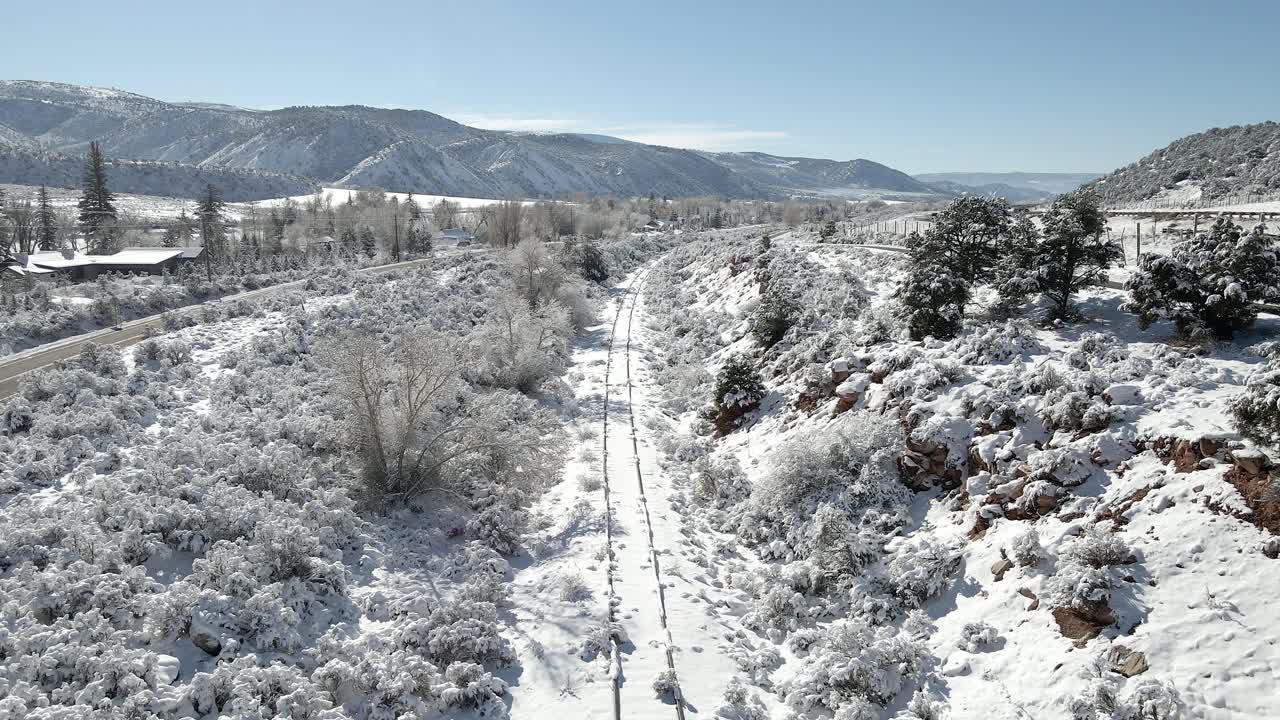Snow Covered Railroad Tracks in Mountain Valley