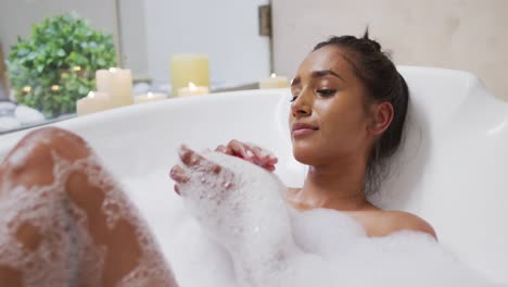 Mixed-race-woman-lying-in-a-bathtub-at-home