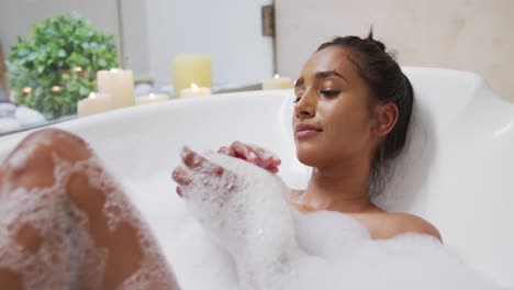 mujer de raza mixta acostada en una bañera en casa