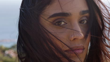 close up portrait of beautiful indian woman enjoying peaceful sunny day relaxing on summer vacation with wind blowing hair