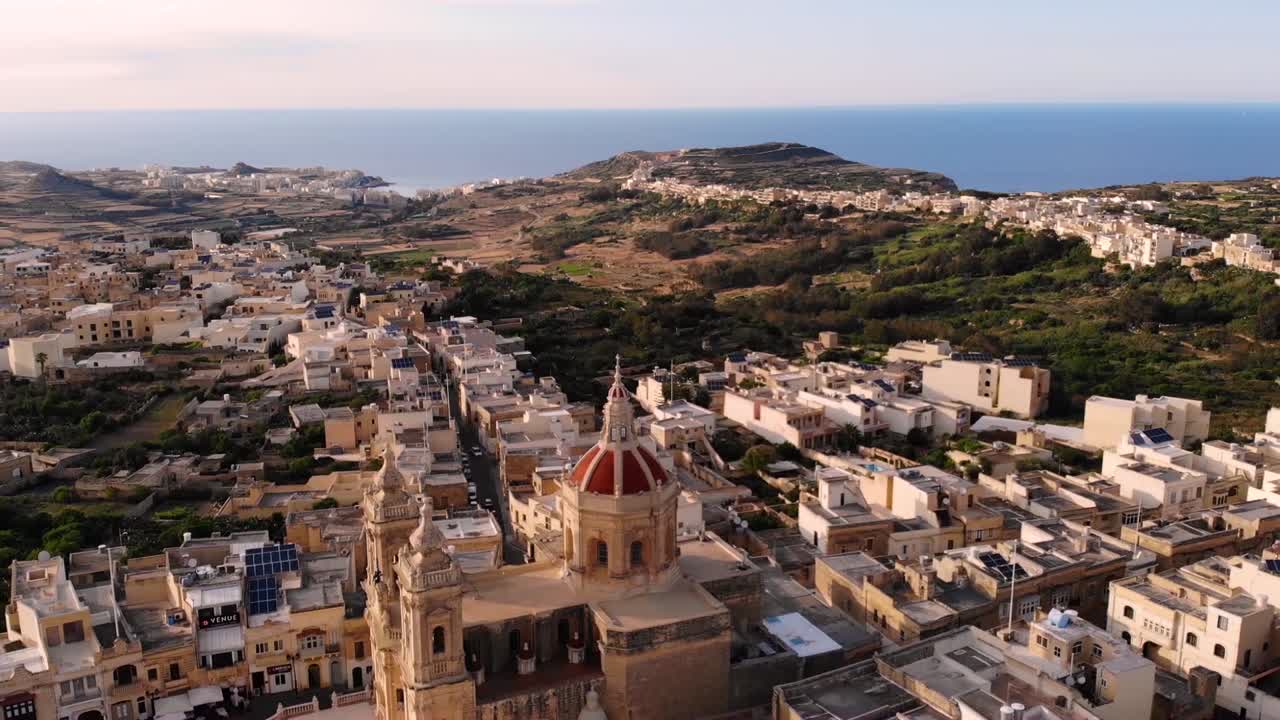 Xaghra Parish Church aerial pan shot church reveal fly backward. Gozo, Malta in summer hot day.